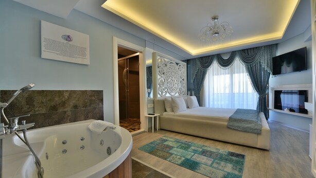 A modern bedroom with a large bed, a sitting area, a bathtub, and a TV. - Kartepe Kosku (Kartepe)