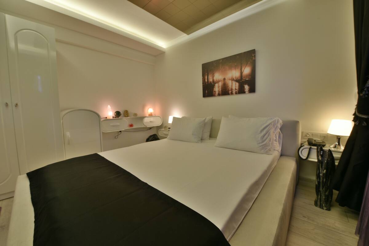 Habitación de hotel con cama, mesitas de noche, armario y un cuadro en la pared.