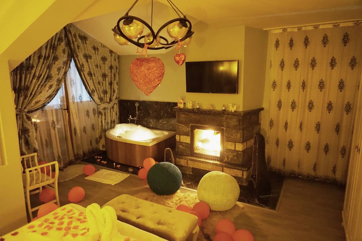 Una habitación acogedora con chimenea, un ventanal con cortinas, una cama y una bañera.