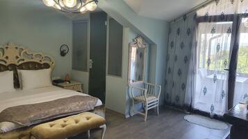 Un dormitorio con cama, un banco, una silla, un espejo y una ventana con cortinas.