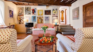 A cozy living room with patterned furniture, a central coffee table with fruit, and artwork on the walls. - Rome as you feel - Cappellari 35 (Rome)