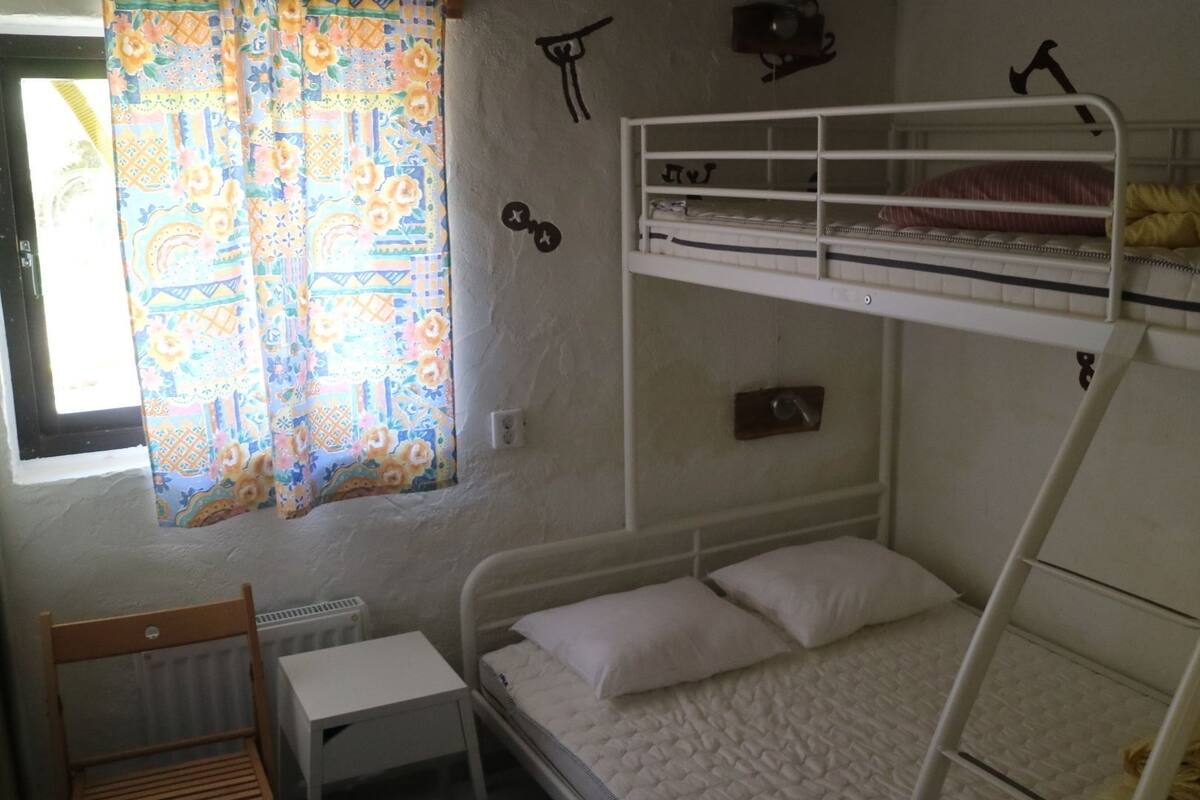 Une chambre avec un lit superposé, une fenêtre, un radiateur et une chaise.