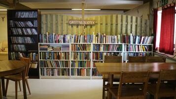 Una biblioteca con estanterías de madera llenas de libros, una mesa de madera y sillas.