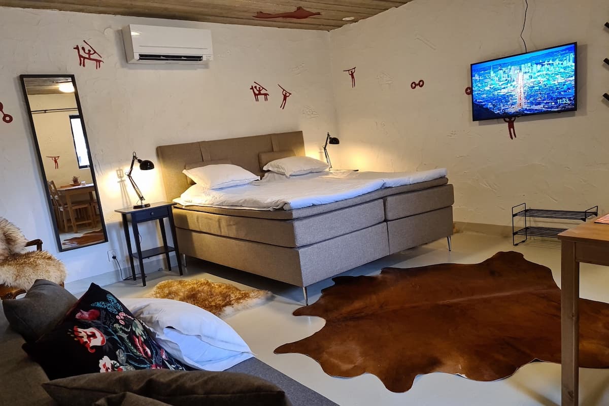 Une chambre à coucher comprenant un lit, un bureau, une chaise, un miroir, un téléviseur et un tapis en peau de vache.