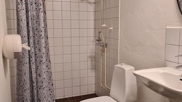 A bathroom with a shower, toilet, sink, and a patterned shower curtain.
