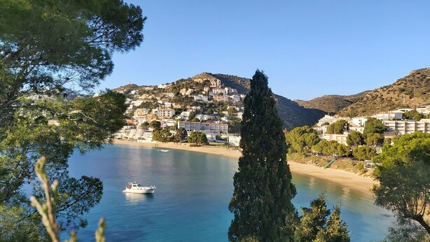 A coastal town with buildings on a hillside, a clear blue sea, and a boat. - Stunning seaview apartment 2 terraces barbecue private parking 5m from the beach (Roses)