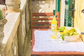 Una mesa con una botella de jugo de limón, un vaso y un bol de limones sobre un mantel de encaje.