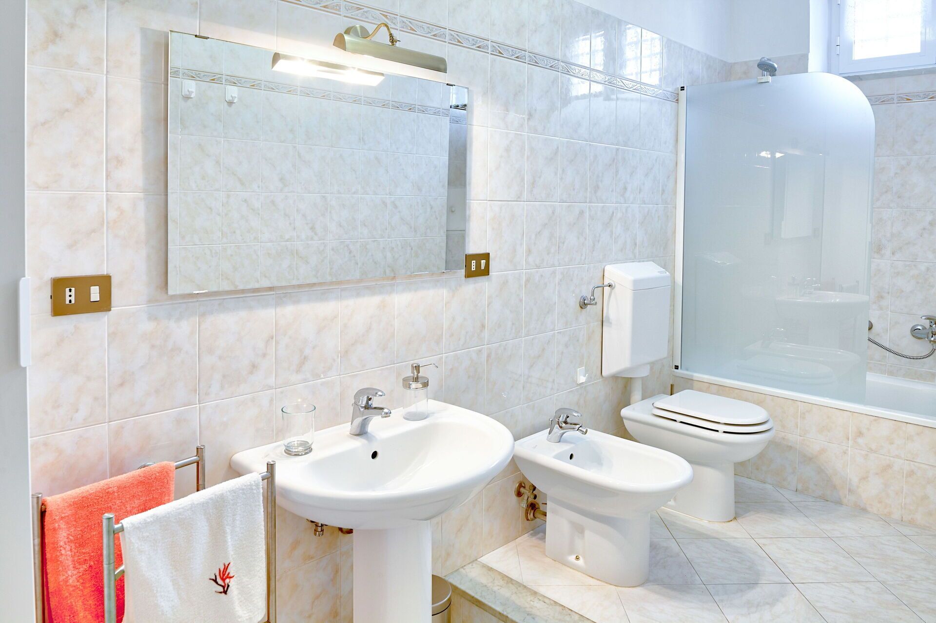 A modern bathroom with two sinks, a toilet, a shower, and a large mirror.