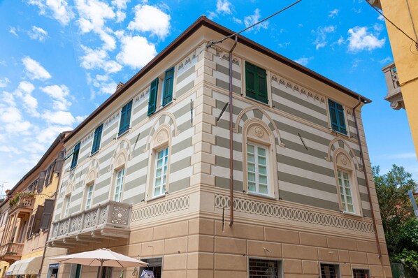 Il s’agit d’un bâtiment historique au style architectural classique, caractérisé par une façade symétrique, des fenêtres en arc de cercle et des moulures décoratives.