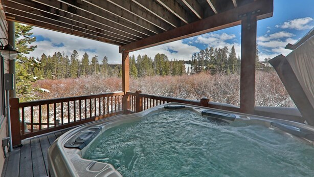 A hot tub on a wooden deck with a view of a forested landscape. - 102 Willows Way 3 Bedroom Townhouse by RedAwning (Winter Park)