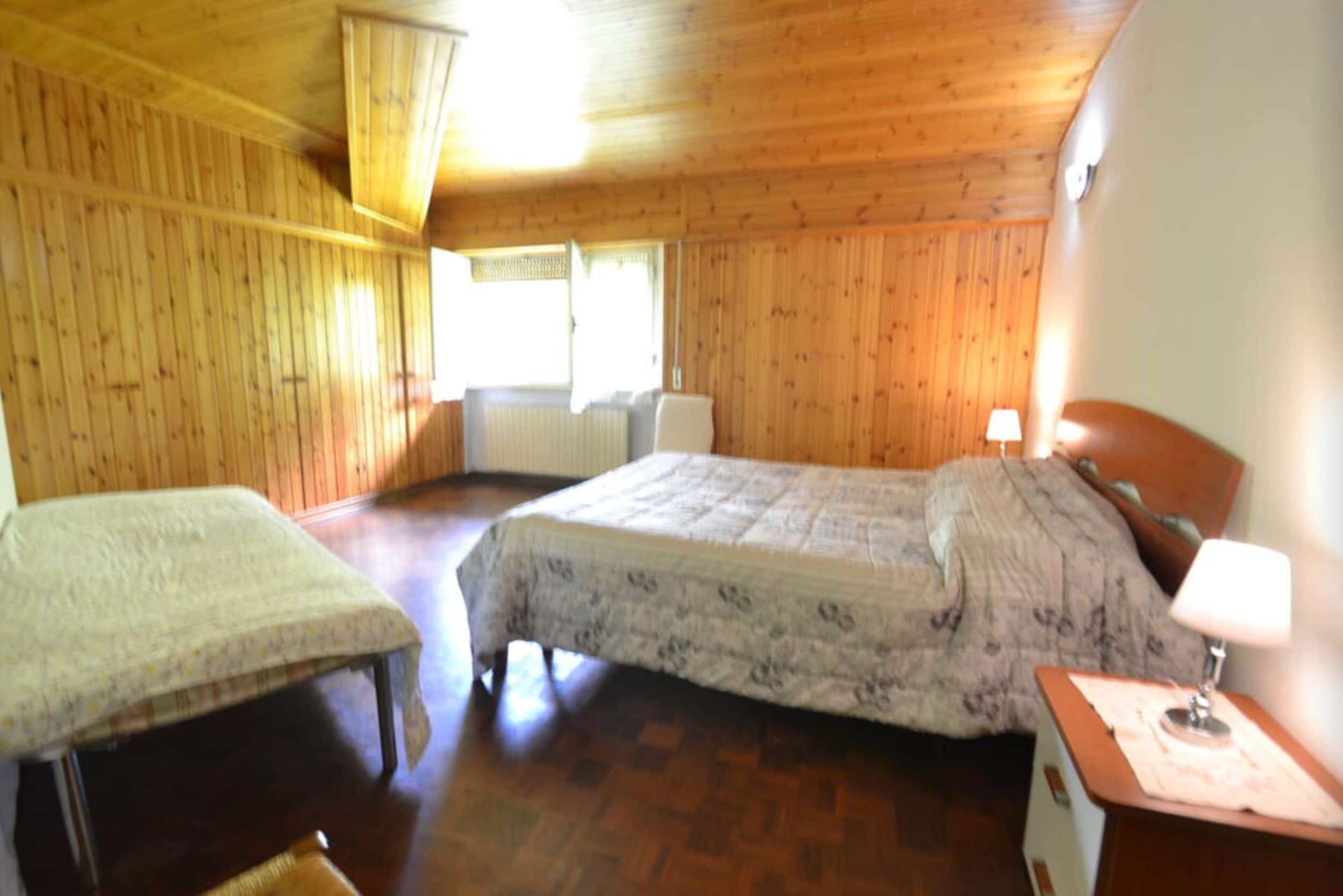 Una habitación con paneles de madera, una cama, una silla y un escritorio.