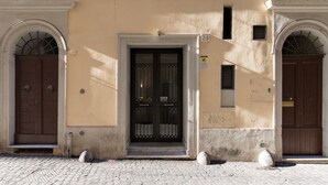 A building with a central entrance door, two side doors, and a small window above the entrance. - Rome as you feel - Design at Colosseum (Rome)