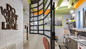 A modern kitchen with a white brick wall, a 'Do What You Love' sign, a 'Bistro' sign, and a view through a glass partition. - Rome as you feel - Design at Colosseum (Rome)
