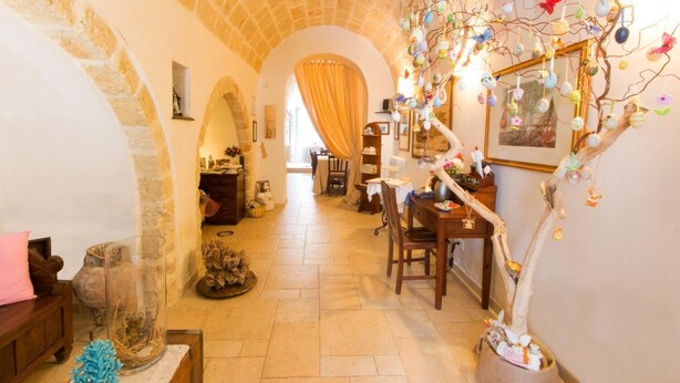A cozy interior with stone arches, a dining area, and a decorative tree with hanging ornaments. - Le Case di Sottovento (Mola di Bari)