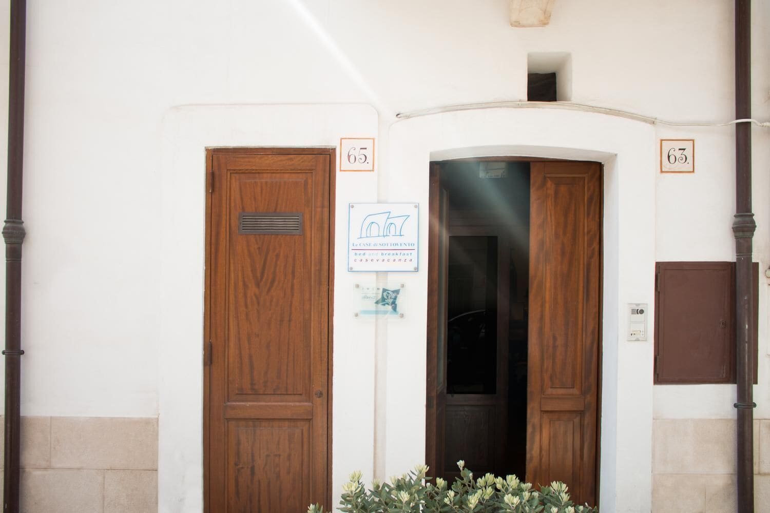 L'ingresso di un edificio con due porte in legno, con le targhe 63 e 65, un cartello che indica un bed and breakfast e una piccola finestra sopra la porta.
