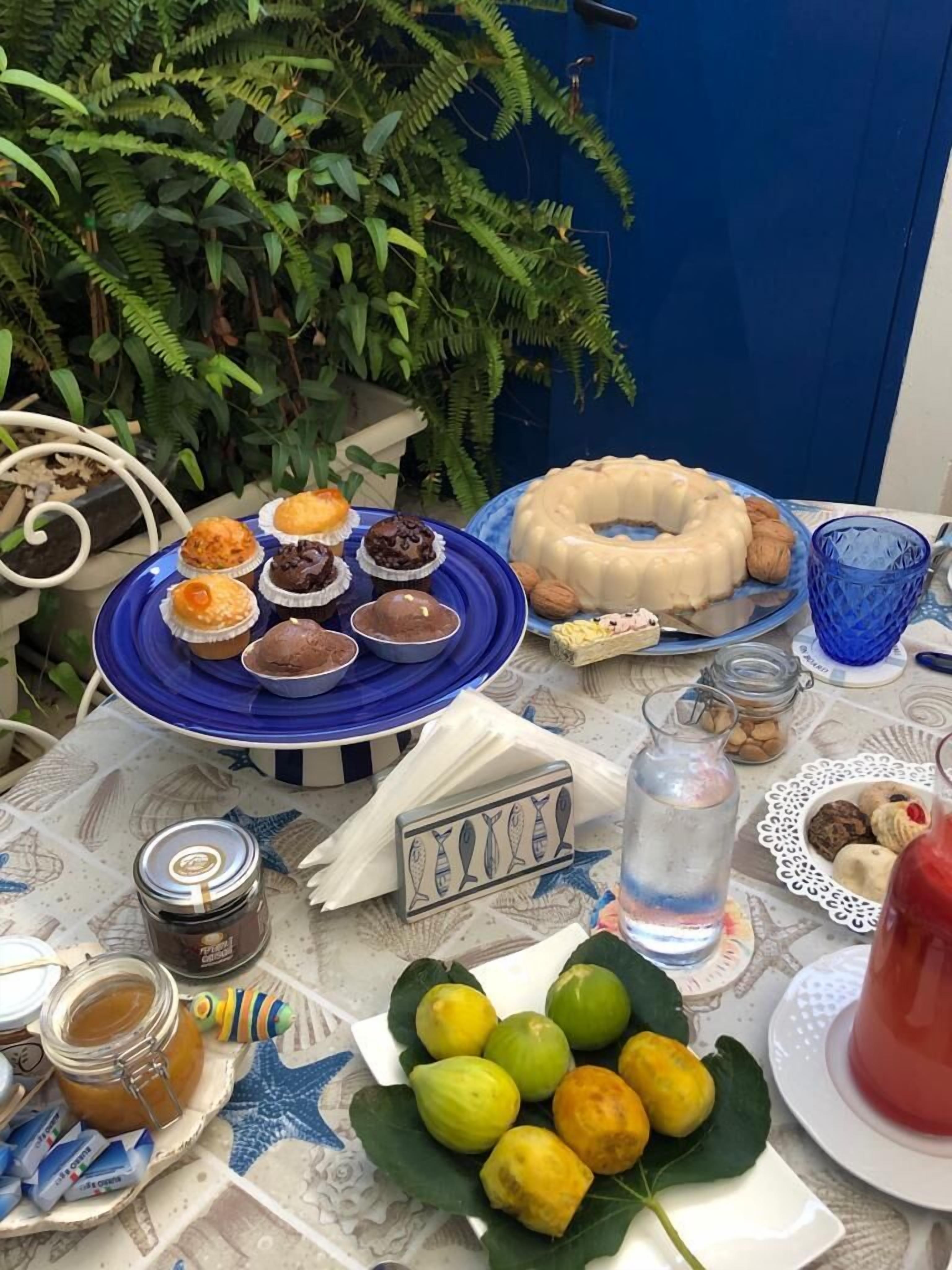 A table set with various food items, including pastries, a bundt cake, and lemons on a patterned tablecloth.