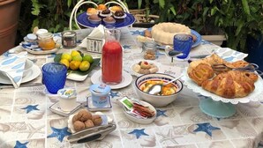 A table set outdoors with various food items and a blue tablecloth. - Le Case di Sottovento (Mola di Bari)