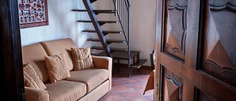 A living room with a sofa, a wooden door, and a staircase.