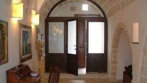 An interior with a wooden table and chair, a painting on the wall, and a doorway leading to another room. - Le Case di Sottovento (Mola di Bari)