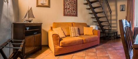 A cozy living room with a sofa, wooden cabinet, and a staircase.