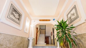 Una imponente escalera con escalones de mármol y columnas blancas, que conduce a una puerta en la parte superior.