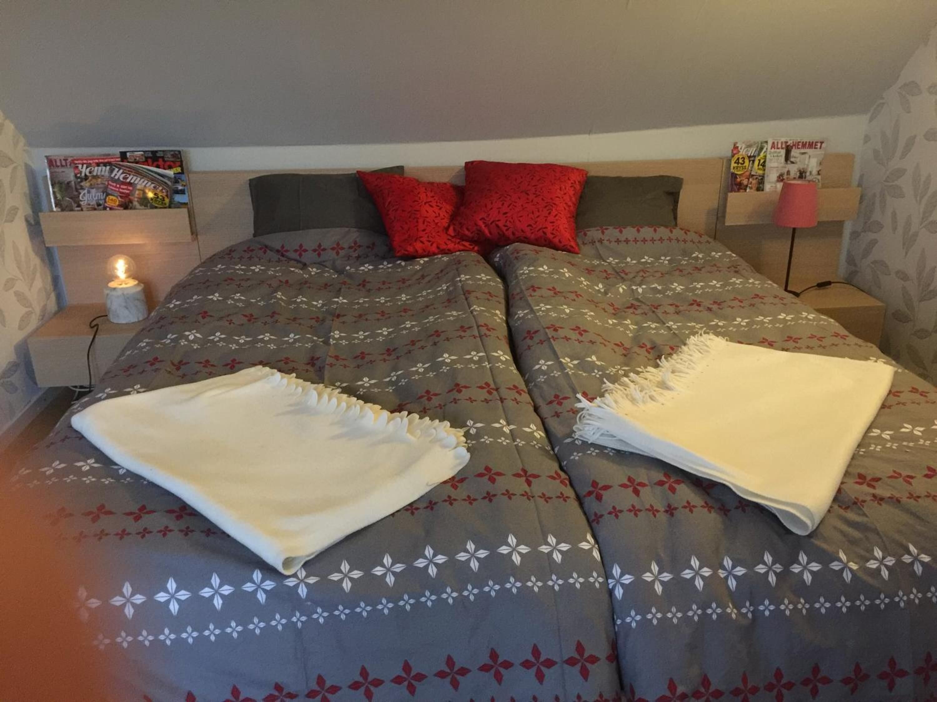 A neatly made bed with a floral patterned bedspread, two pillows, and a folded white blanket on the bed.