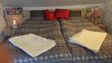A neatly made bed with a floral patterned bedspread, two pillows, and a folded white blanket on the bed.