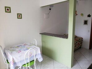 A small dining area with a table and chairs, a green accent wall, and a small kitchen counter.