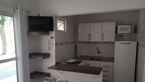 A compact kitchen with a built-in microwave, a sink, and a refrigerator. There are bar stools and a small window. - Pousada Barra Nativa (Florianópolis)