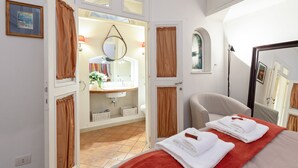 Une chambre d’hôtel comprenant un lit, une salle de bain avec un lavabo et un miroir, et une chaise.