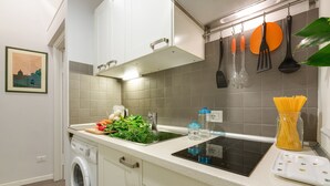 Une cuisine moderne équipée d’un lave-linge intégré, d’un évier et de divers ustensiles de cuisine.
