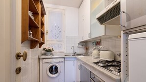 Une cuisine de taille réduite équipée d’un lave-linge, d’une cuisinière et d’un évier.