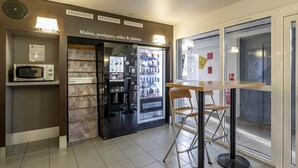 A kitchenette with a microwave, refrigerator, and beverage dispenser. - B&B Hotel Bordeaux Merignac Hotel De Ville (Merignac)