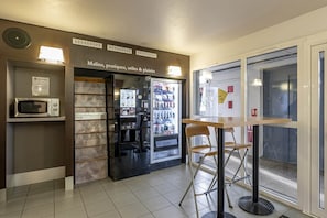 Uma cozinha compacta com micro-ondas, frigorífico e dispensador de bebidas.