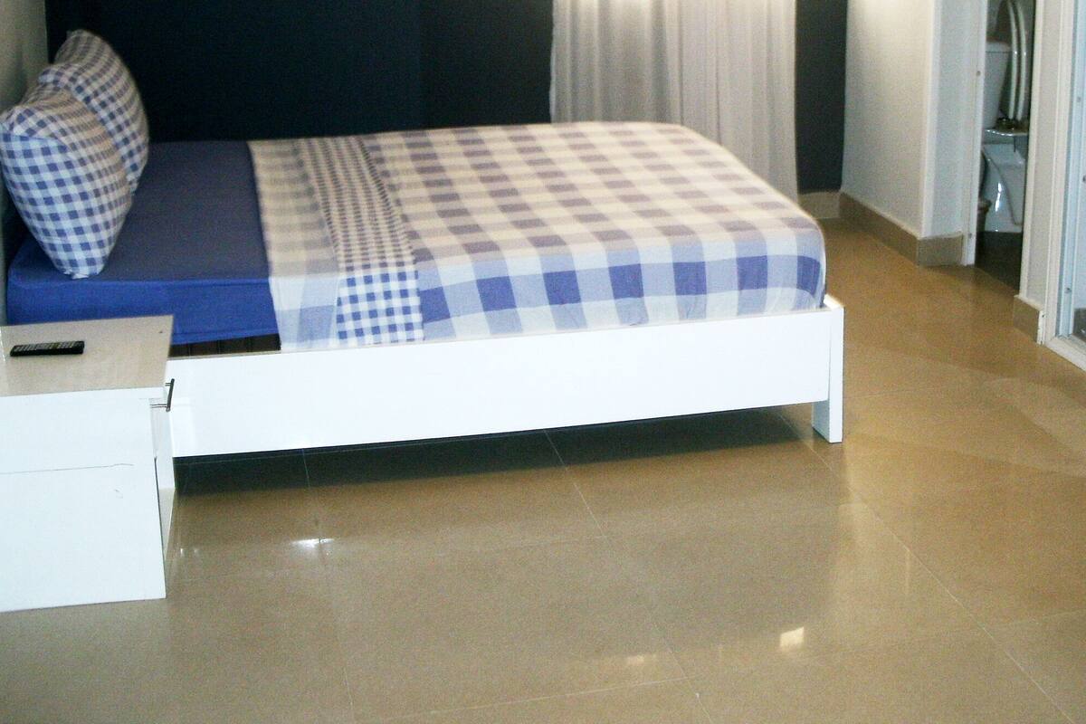 Ein kleines, ordentlich eingerichtetes Schlafzimmer mit einem Einzelbett, einem Nachttisch und einem Spiegel.