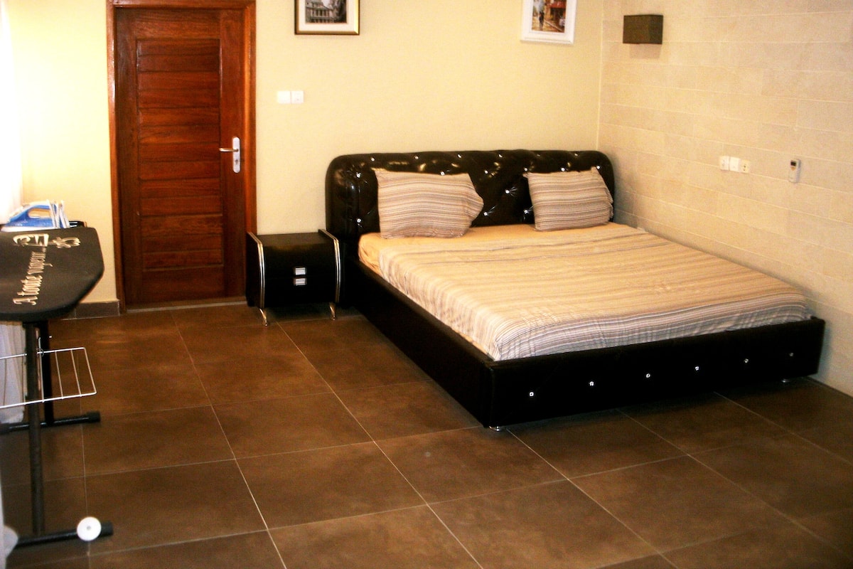 Ein Schlafzimmer mit einem Bett, einer Holztür, einem kleinen Nachttisch und einer Wandleuchte.