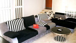 A living room with a grey sofa, black and white striped pillows, and a round coffee table.