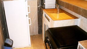 A compact kitchen with a white refrigerator, a microwave, a sink, and a stove.