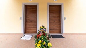 A building facade with two wooden doors, a tiled entrance area, and a flower arrangement in the foreground. - Il Mandorlo b&b (Florence)