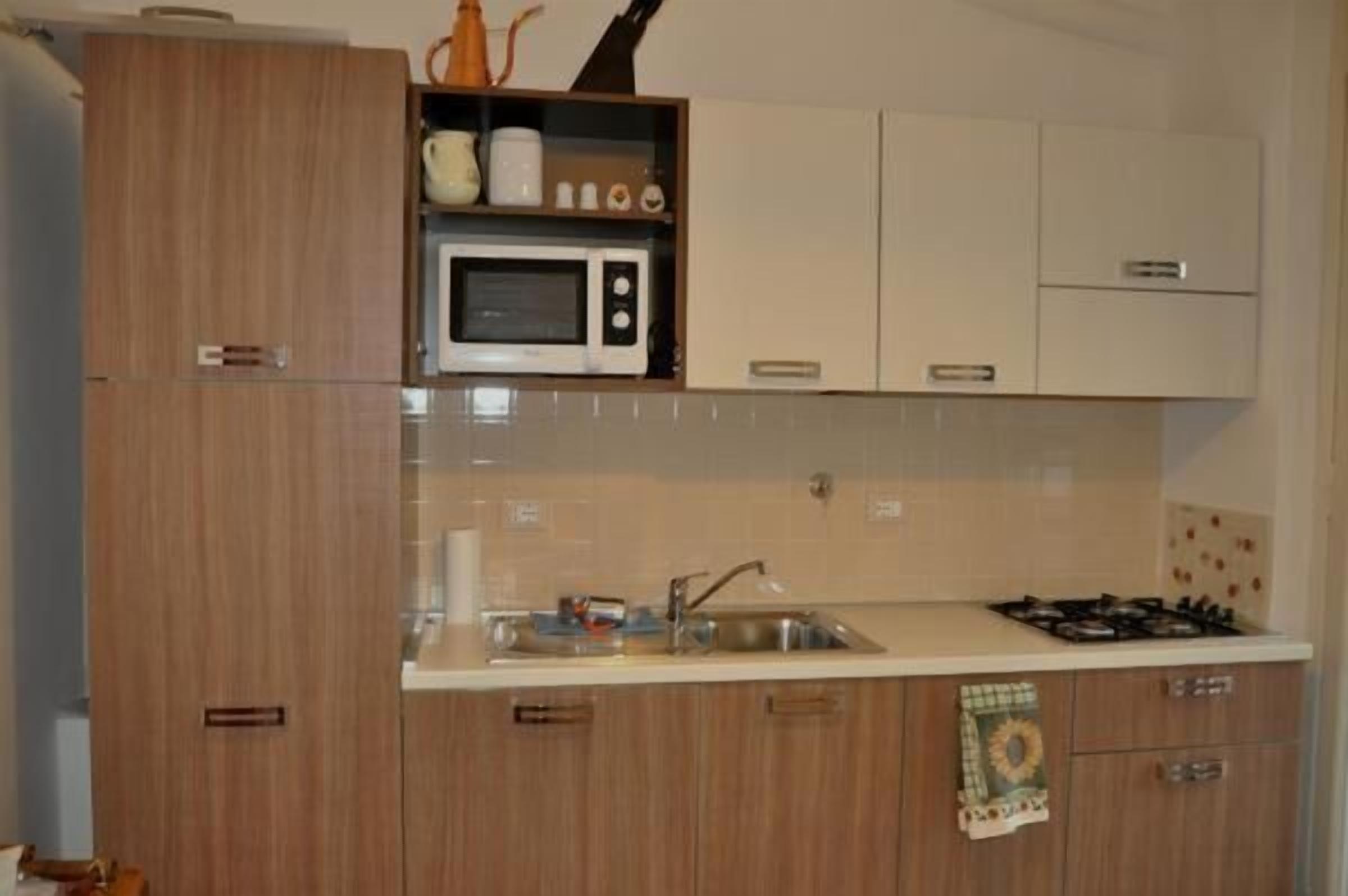 A kitchen with wooden cabinets, a microwave, a sink, and a gas stove.
