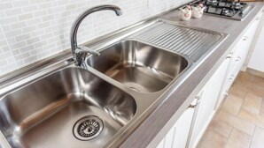 A stainless steel kitchen sink with a modern faucet, a double sink, and a stainless steel range with a gas stove. - Il Mandorlo b&b (Florence)