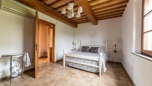 A bedroom with a wooden ceiling, a bed with patterned bedding, a bedside table, and a window. - Il Mandorlo b&b (Florence)