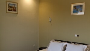 Ein Schlafzimmer mit einem Bett, einer Wandleuchte und zwei gerahmten Bildern.