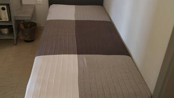 A small, neatly made bed with a striped bedspread and a headboard.