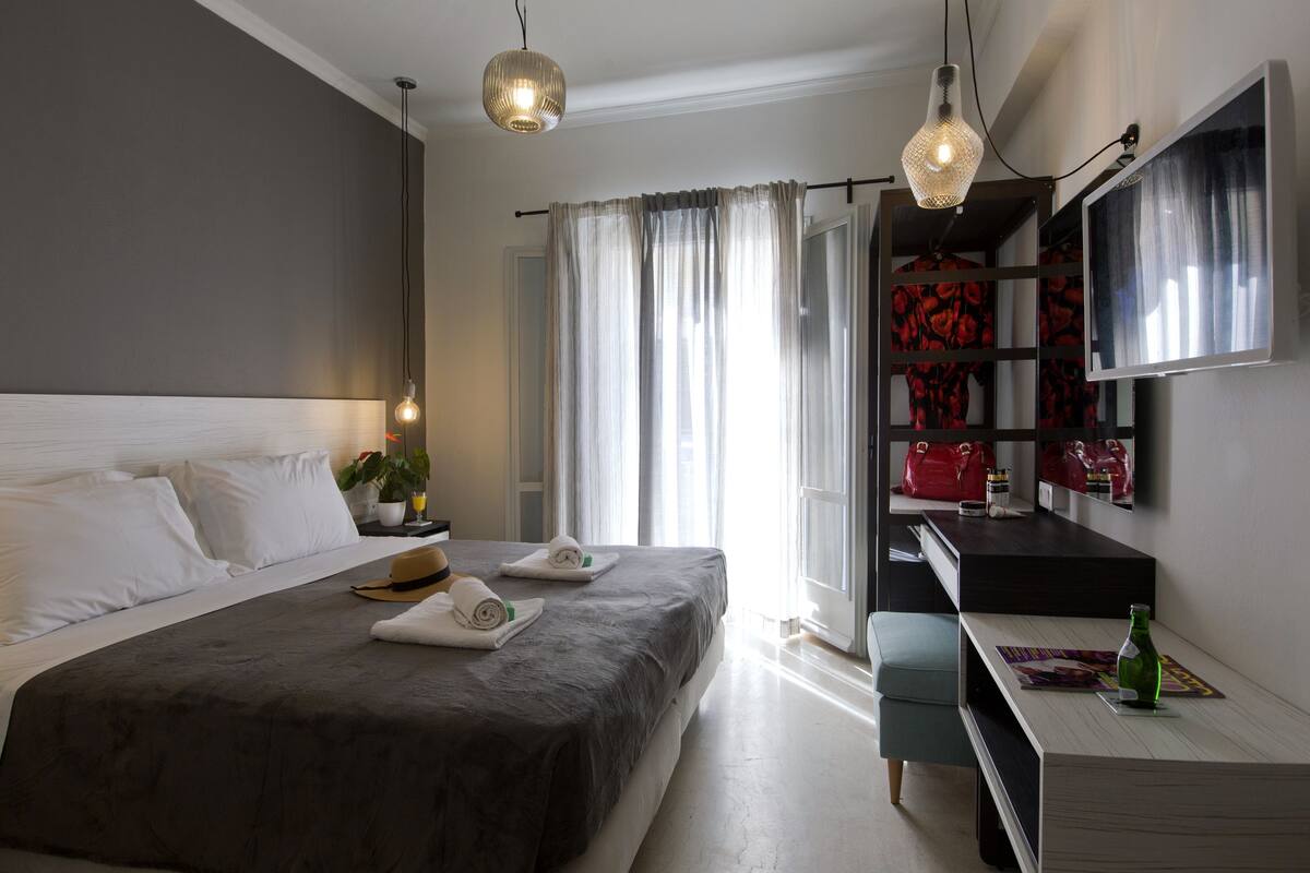 A modern hotel room with a large bed, bedside tables, a desk, and a television.