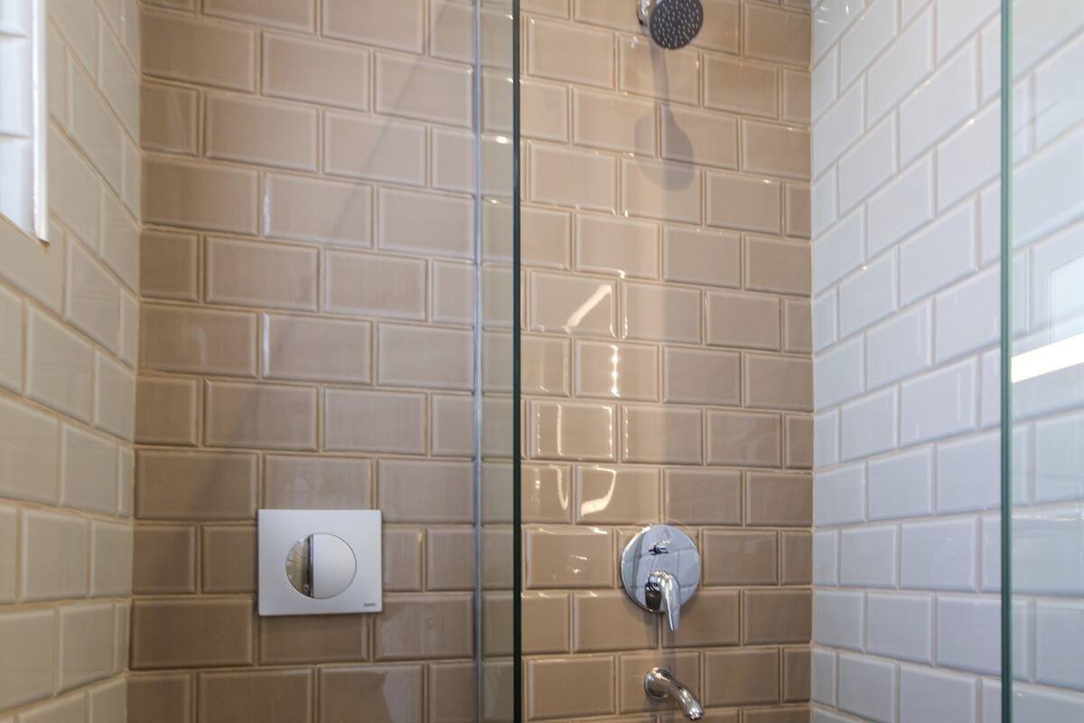 A bathroom with a glass-enclosed shower, a toilet, and a towel rack.