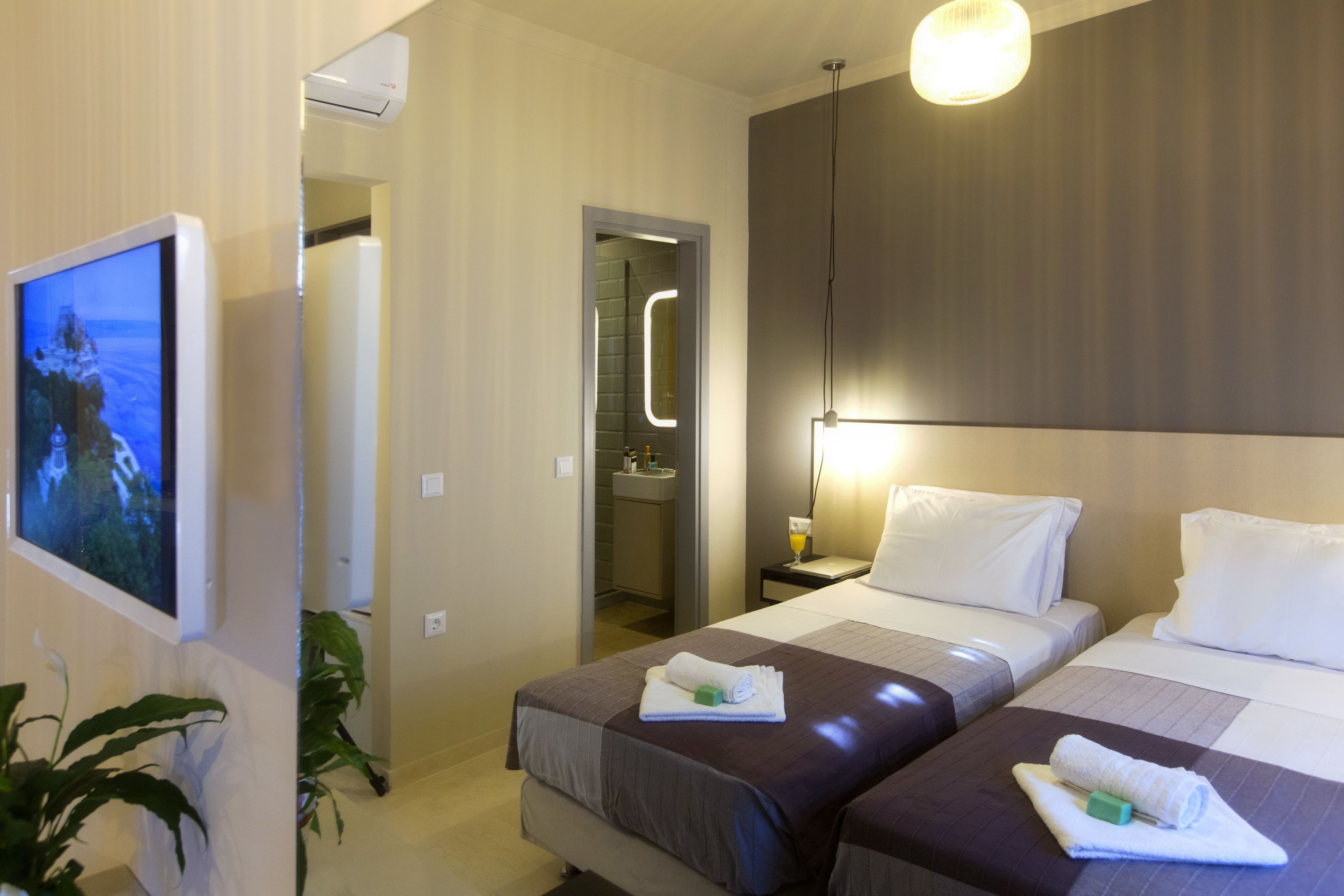 A hotel room with two beds, a TV, and a bathroom visible through an open door.