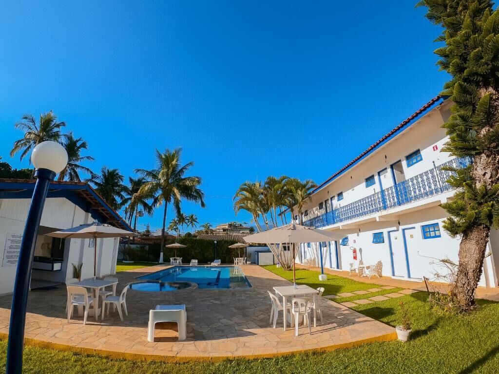 A hotel with a swimming pool, outdoor seating, and palm trees.