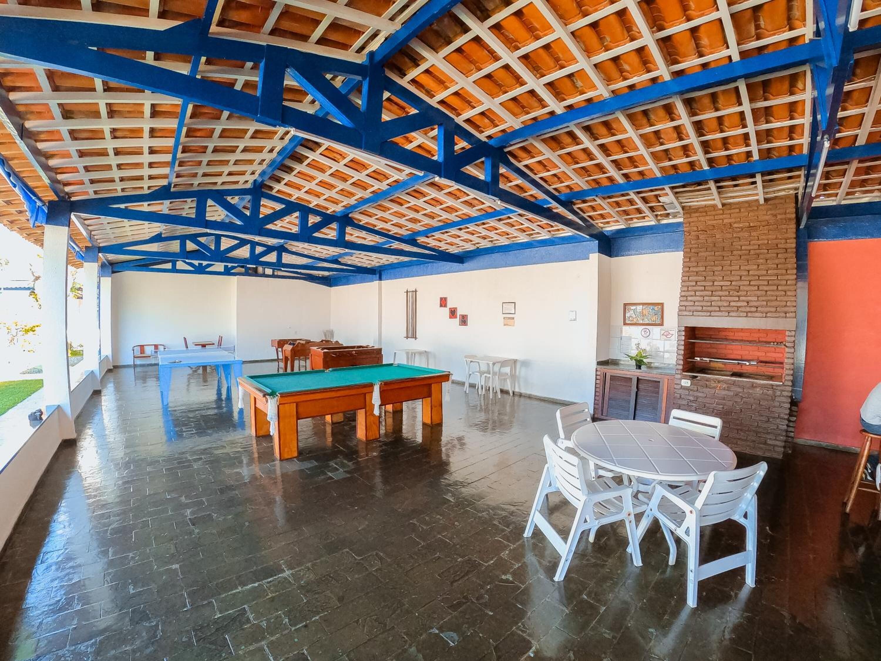 A spacious indoor area with a pool table, chairs, and a brick fireplace.