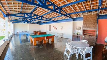 A spacious indoor area with a pool table, chairs, and a brick fireplace.
